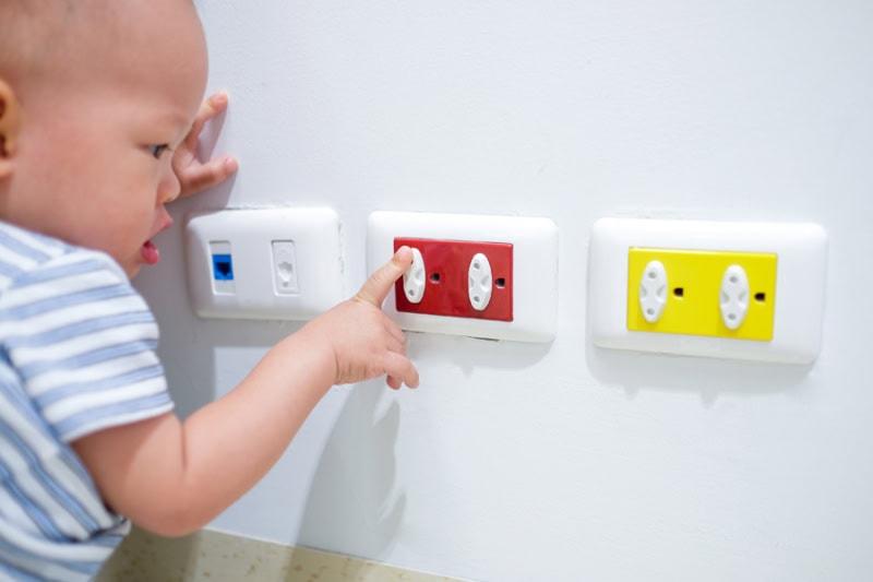 Electrical Safety Tips. Curious toddler baby boy child play with electric plug.