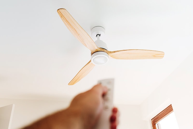 How to Choose the Right Ceiling Fan. A person controlling a ceiling fan.